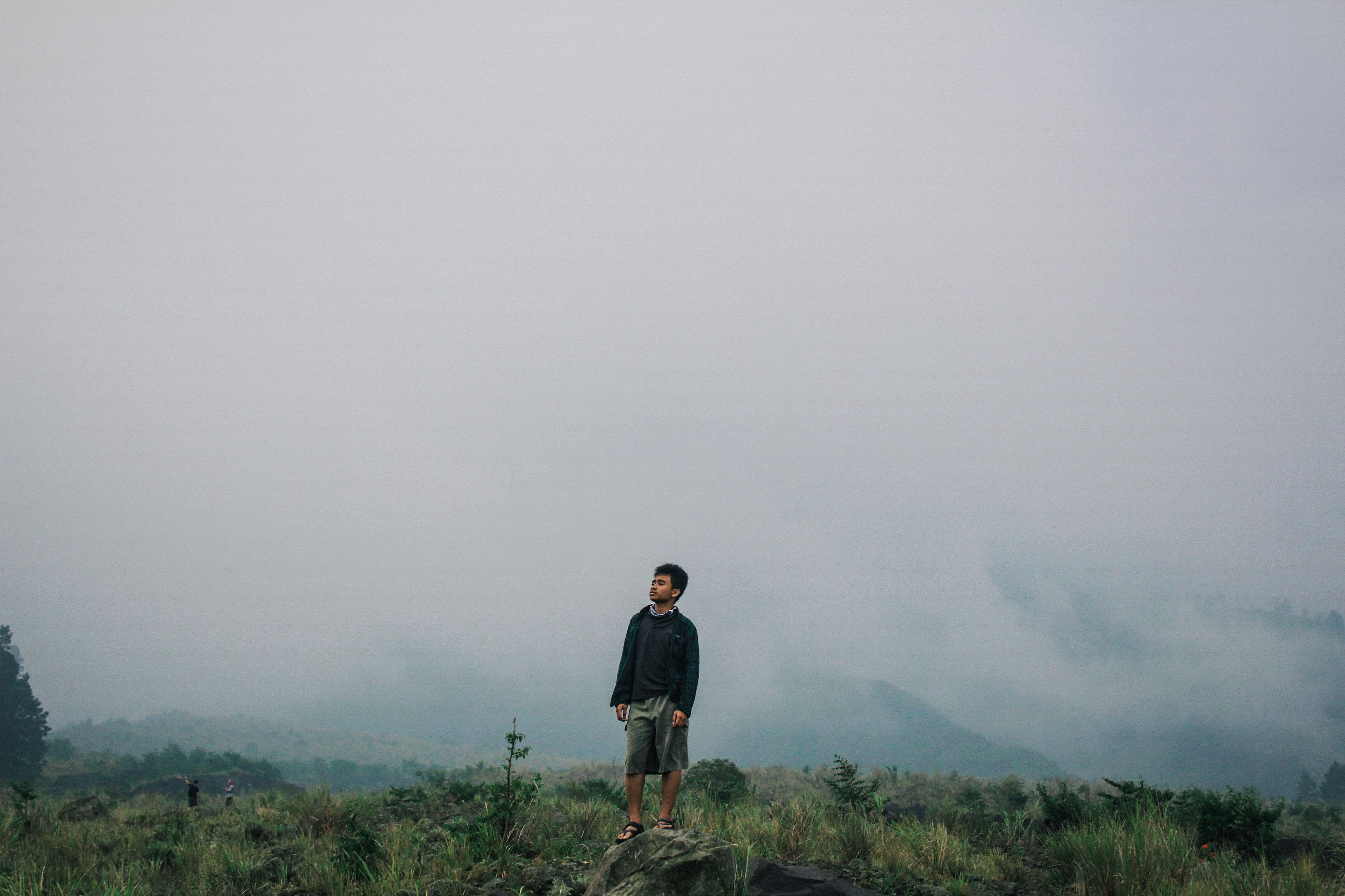 man standing on gray stone under cloudy sky